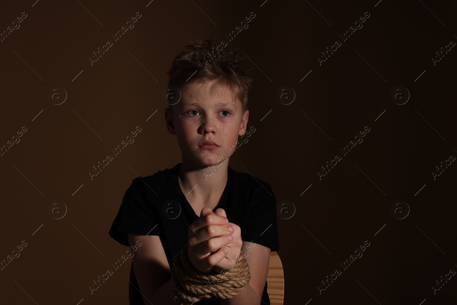 Photo of Little boy tied up and taken hostage on dark background