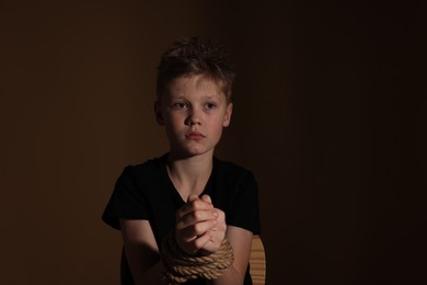 Photo of Little boy tied up and taken hostage on dark background
