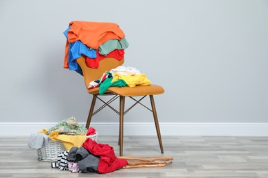 Photo of Different clothes, chair and wicker basket near grey wall