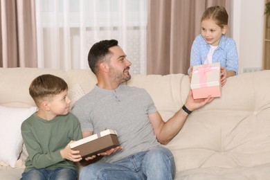 Photo of Cute little children presenting their father with gifts at home