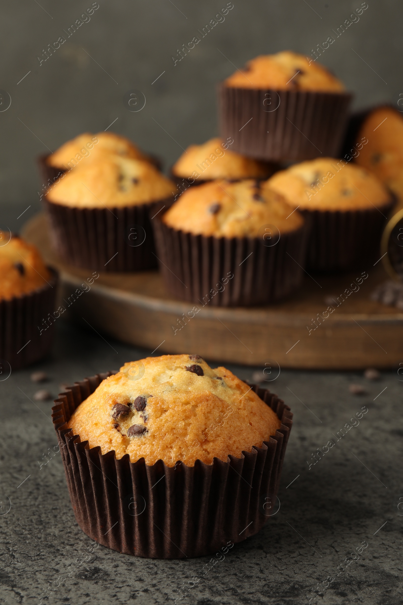 Photo of Delicious freshly baked muffins with chocolate chips on gray table, closeup