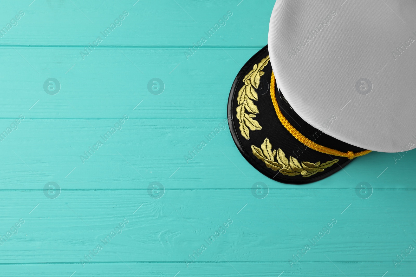 Photo of Peaked cap with accessories on turquoise wooden background, top view. Space for text