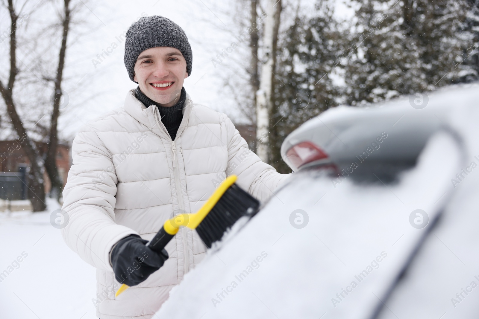 Photo of Man cleaning snow from car window outdoors