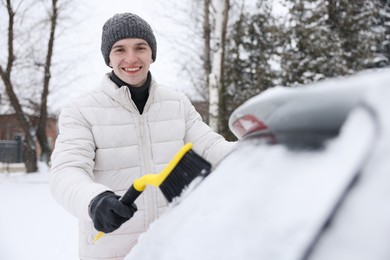 Man cleaning snow from car window outdoors