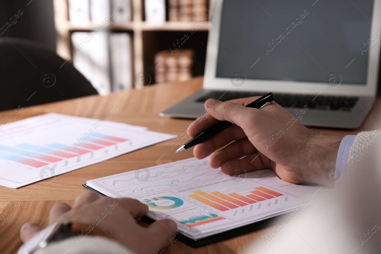 Photo of Businessman working with charts and graphs at table in office, closeup. Investment analysis