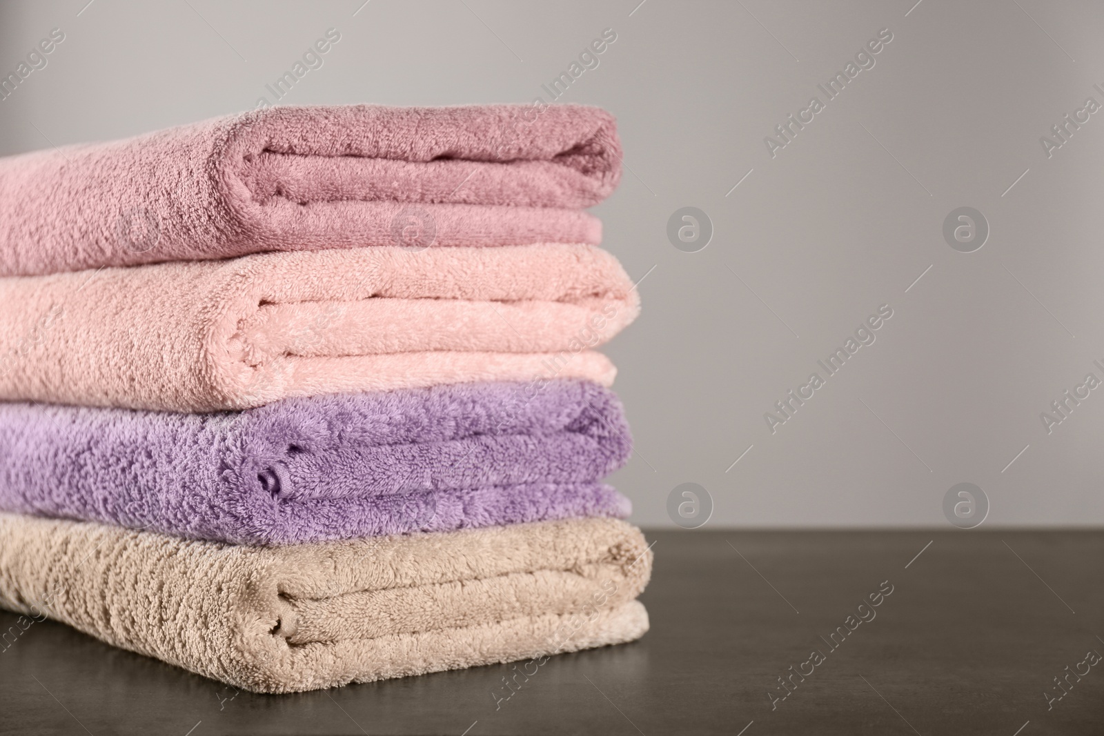 Photo of Stack of clean bath towels on dark grey table. Space for text