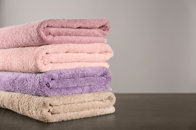 Stack of clean bath towels on dark grey table. Space for text