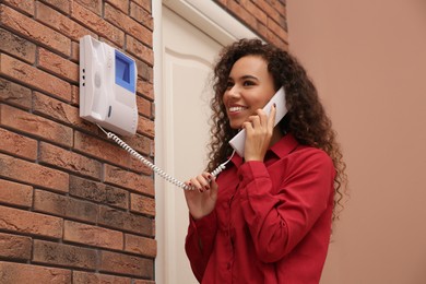 Photo of Young African-American woman answering intercom call indoors