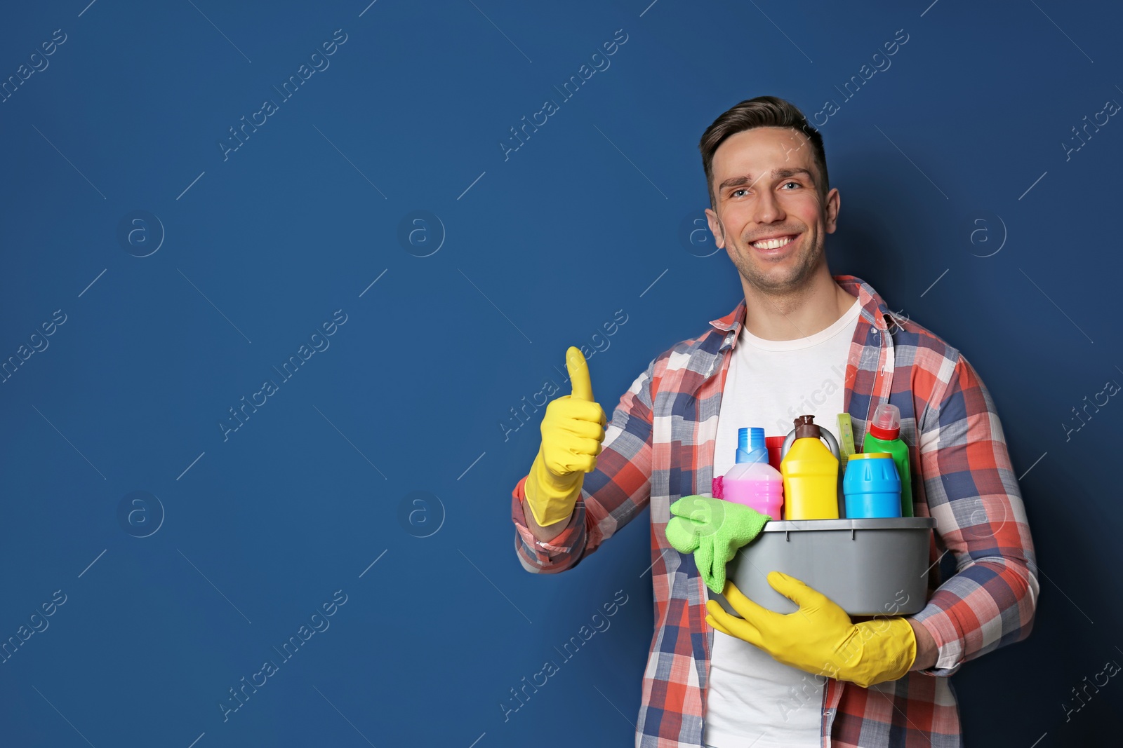 Photo of Man with basin of detergents on color background. Space for text