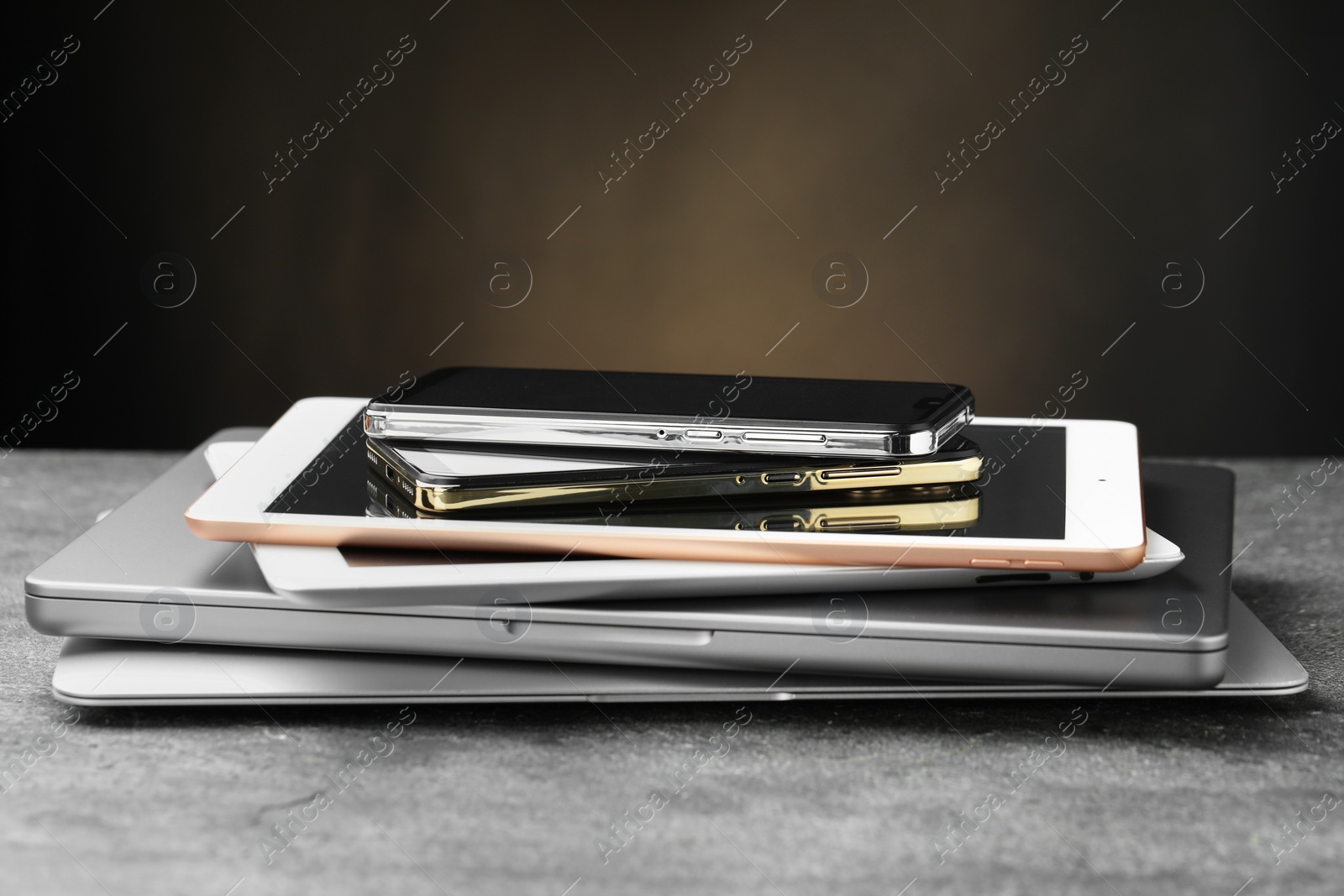 Photo of Stack of electronic devices on grey table, closeup. Space for text