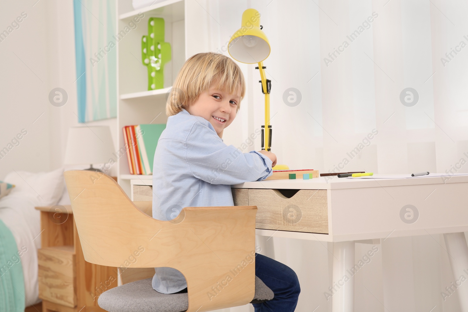 Photo of Boy sitting at desk in room. Home workplace