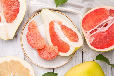 Photo of Different tasty pomelo fruits on white wooden table, flat lay
