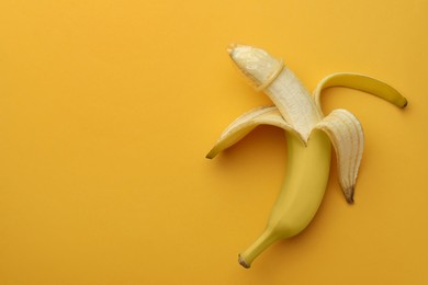 Photo of Banana with condom on orange background, top view and space for text. Safe sex concept