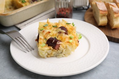 Photo of Tasty sausage casserole with green onions served on grey table, closeup