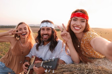 Photo of Happy hippie friends taking selfie in field