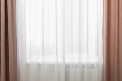 Photo of Elegant window curtains and white tulle indoors. Interior design