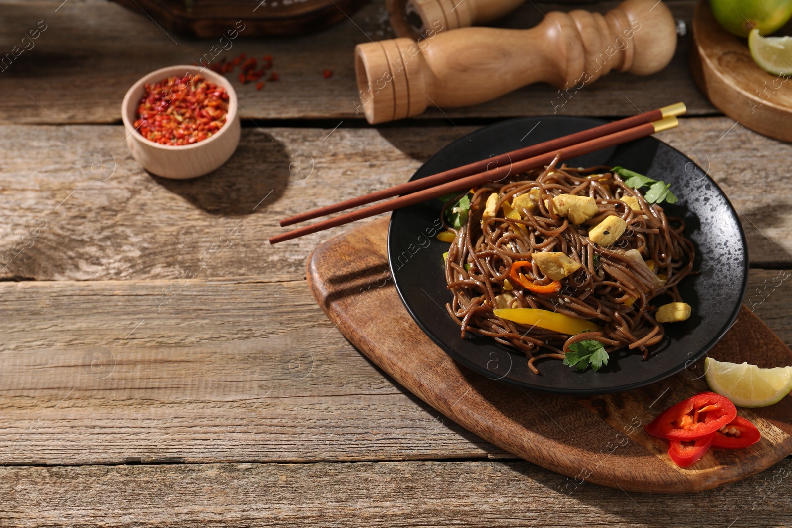 Photo of Stir-fry. Tasty noodles with meat and vegetables served on wooden table, space for text