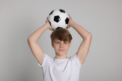 Teenage boy with soccer ball on light grey background