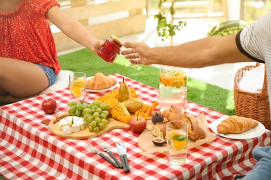 Couple with tasty food imitating picnic at home, closeup