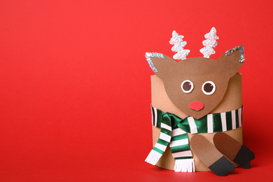 Photo of Toy deer made of toilet paper roll on red background. Space for text