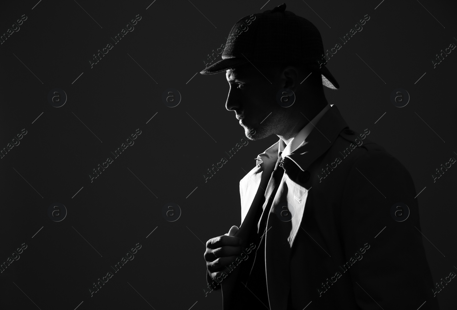 Photo of Old fashioned detective in hat on dark background, black and white effect. Space for text