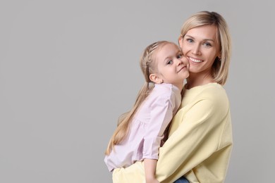 Photo of Family portrait of happy mother and daughter on grey background. Space for text