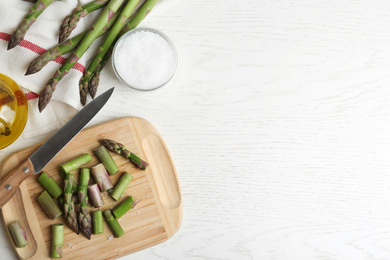 Photo of Fresh raw asparagus on white table, flat lay. Space for text