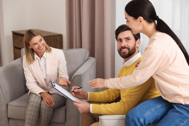 Photo of Real estate agent and couple signing contract in new apartment