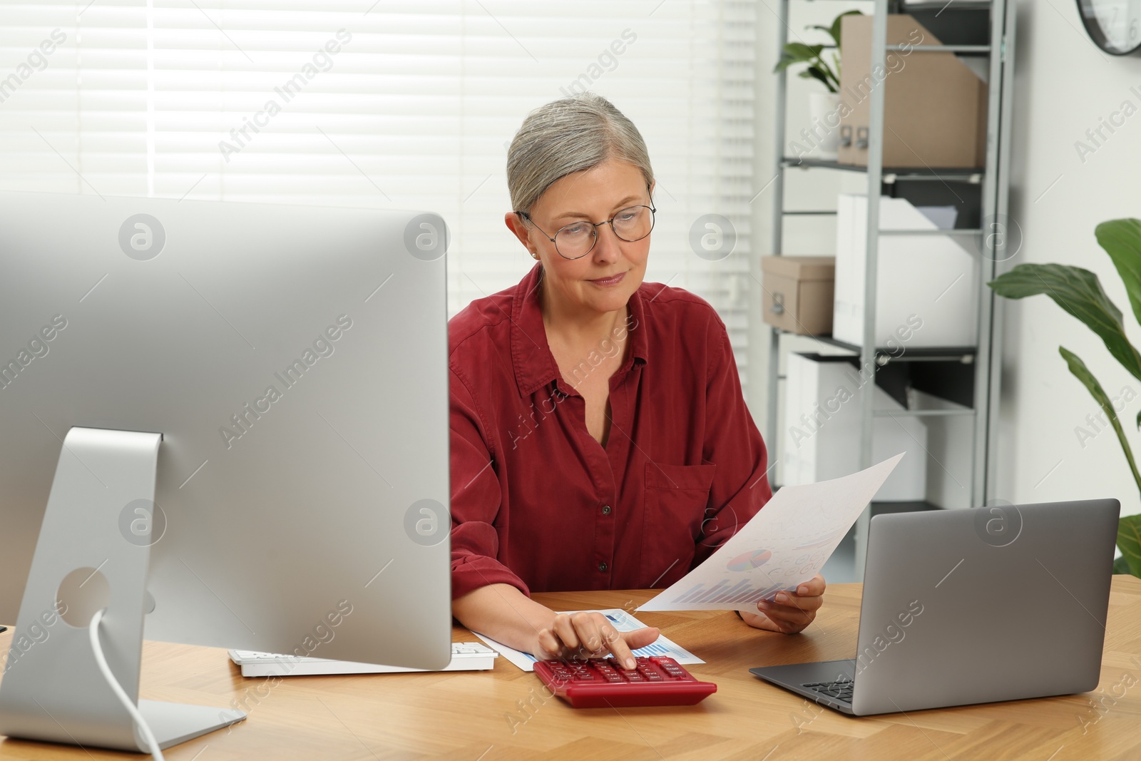 Photo of Senior accountant working at wooden desk in office