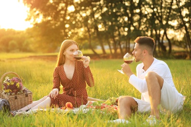 Photo of Young man and his girlfriend having picnic in green park