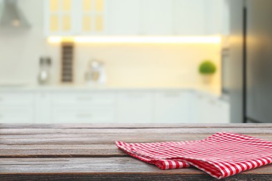 Red checkered napkin on wooden table and blurred view of stylish kitchen interior. Space for design