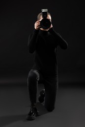 Professional photographer taking picture on black background