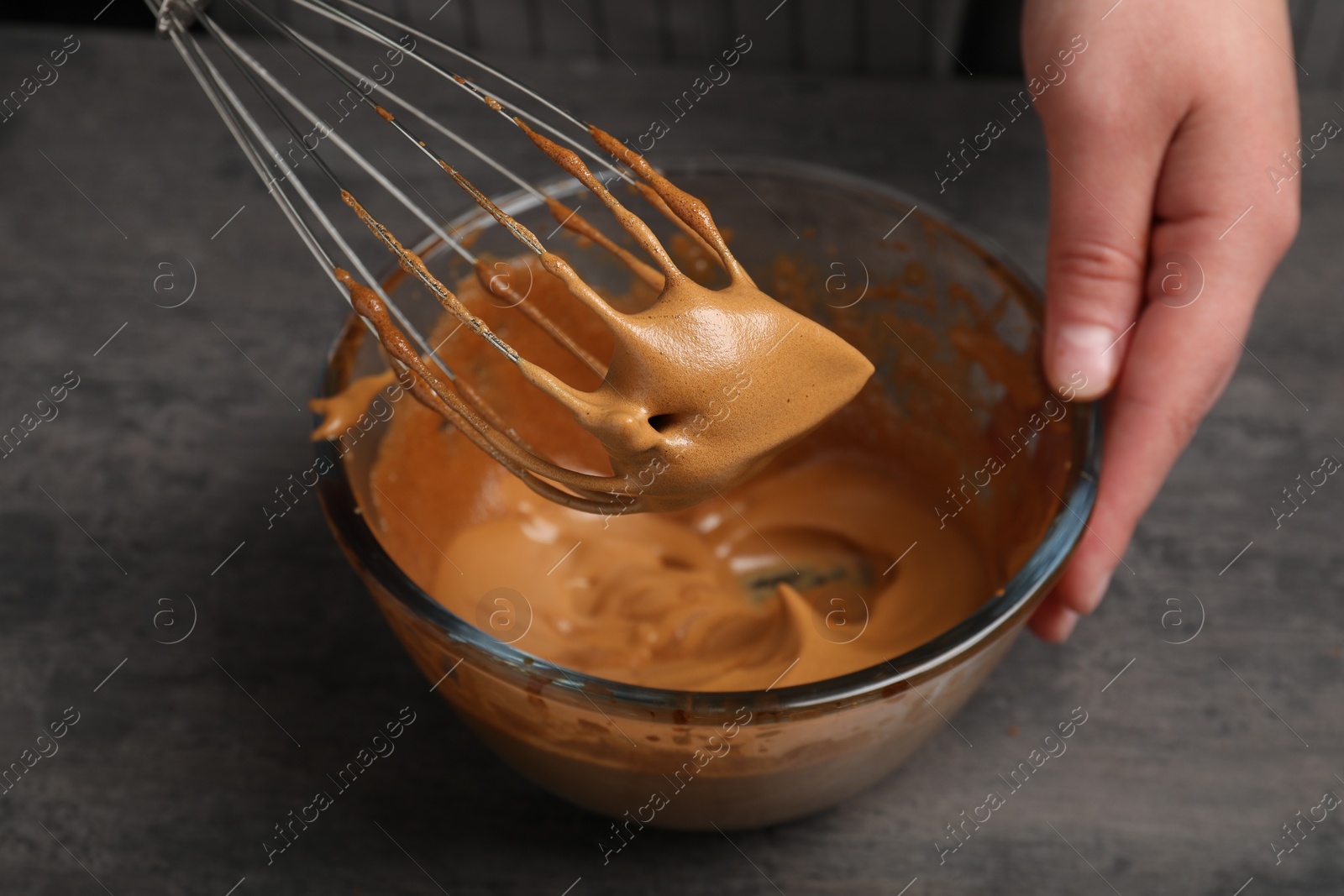 Photo of Woman whipping coffee cream at grey table, closeup