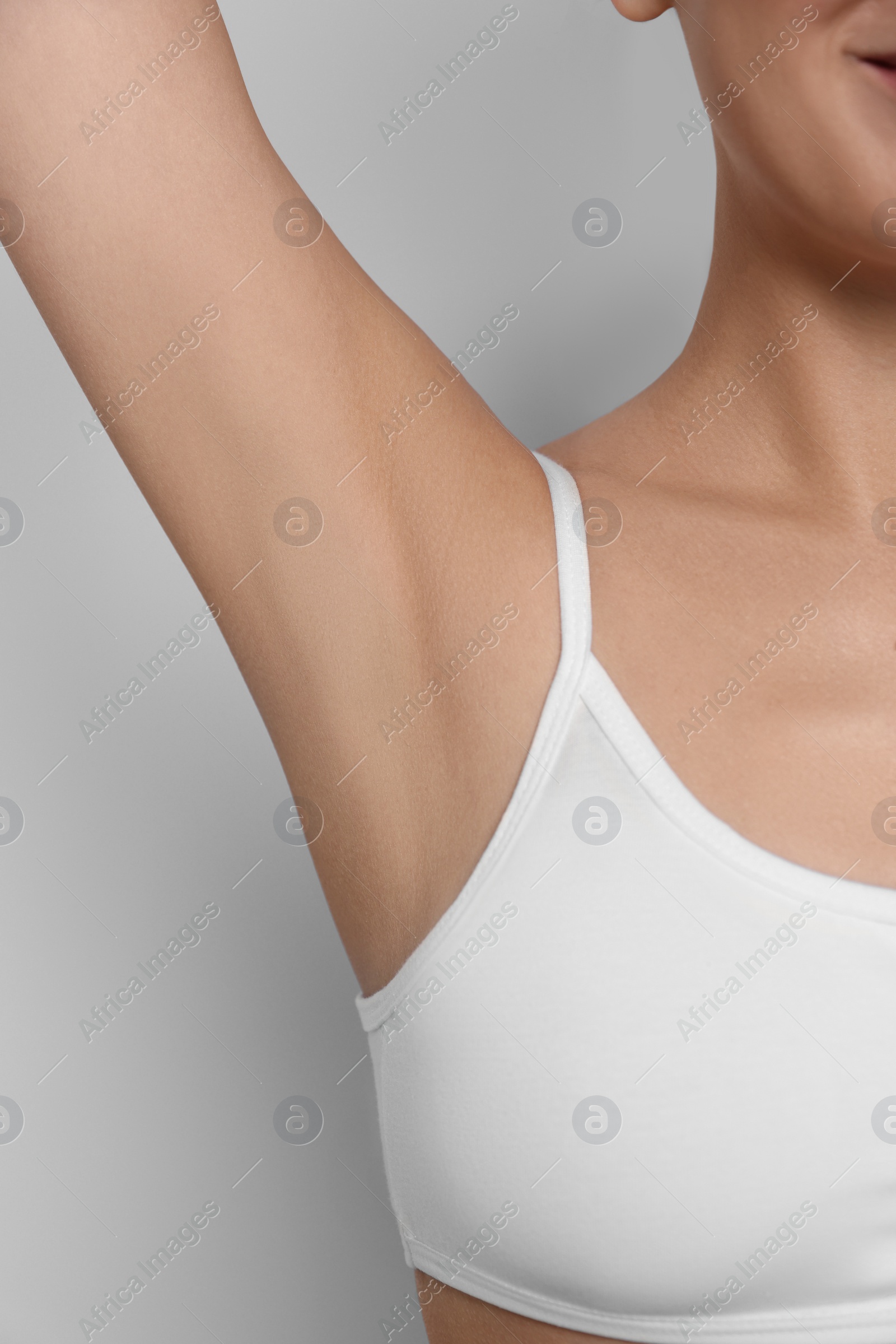 Photo of Young woman showing smooth skin after epilation on white background, closeup