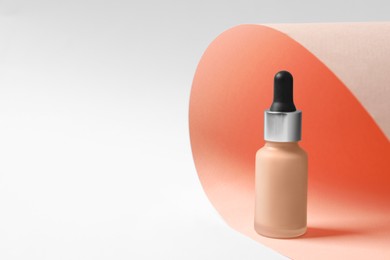 Photo of Bottle of skin foundation on color background, space for text. Makeup product