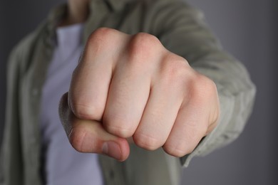 Photo of Man showing fist with space for tattoo on grey background, selective focus