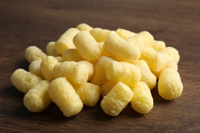 Photo of Pile of delicious crispy corn sticks on wooden table, closeup