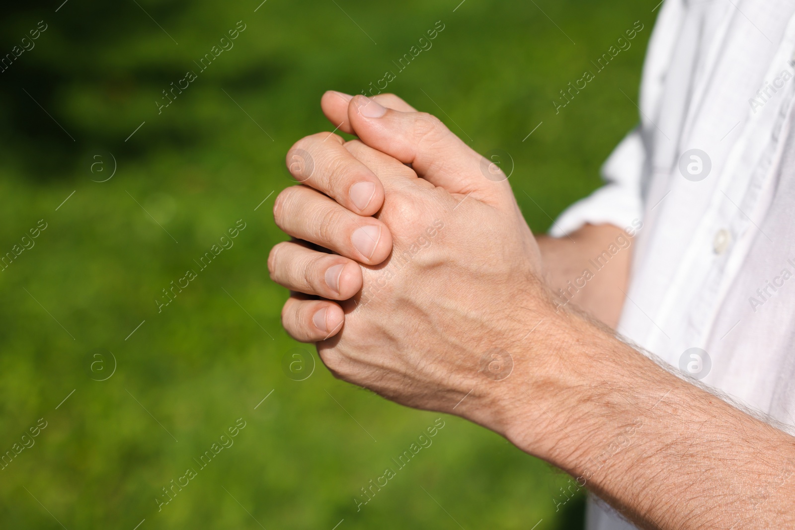 Photo of Man praying outdoors on sunny day, closeup