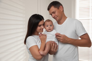 Photo of Happy family. Couple with their cute baby near window indoors