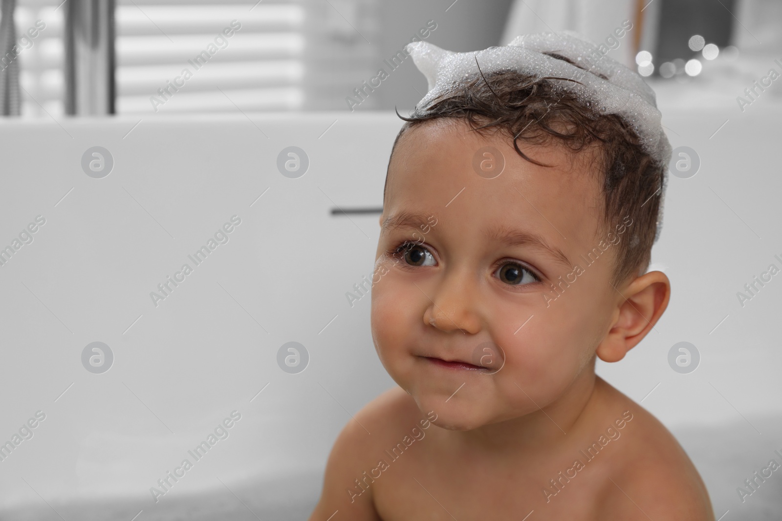 Photo of Cute little boy washing hair with shampoo in bathroom. Space for text