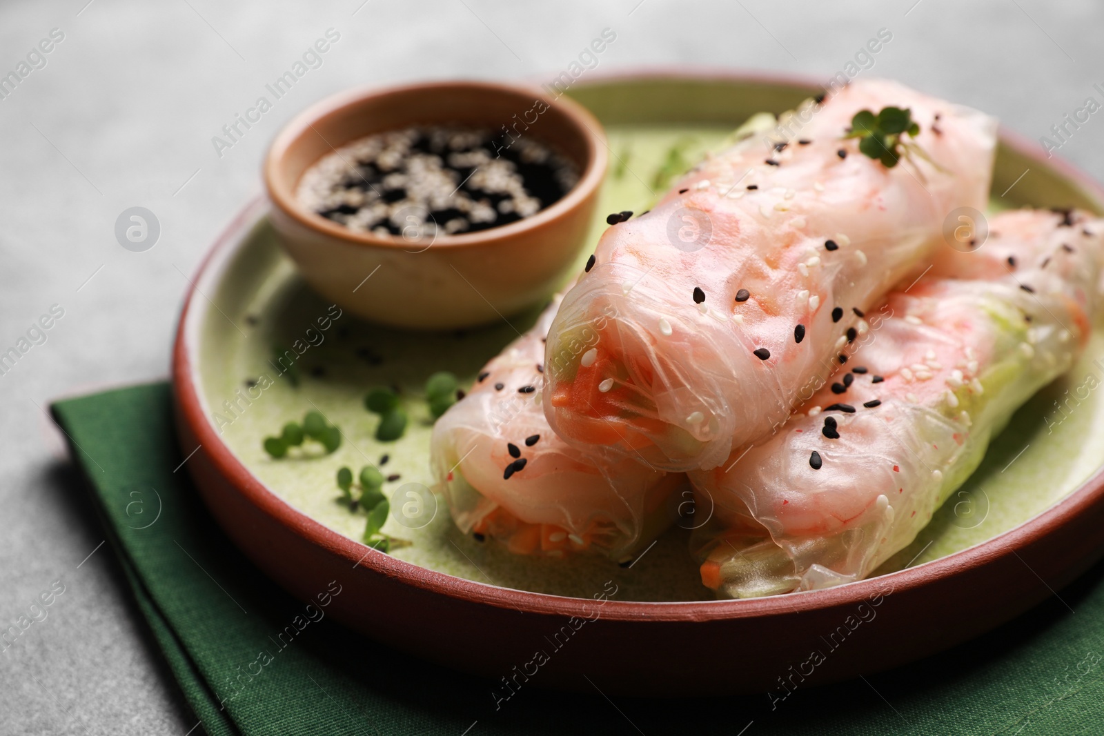 Photo of Tasty spring rolls served with soy sauce on grey table, closeup