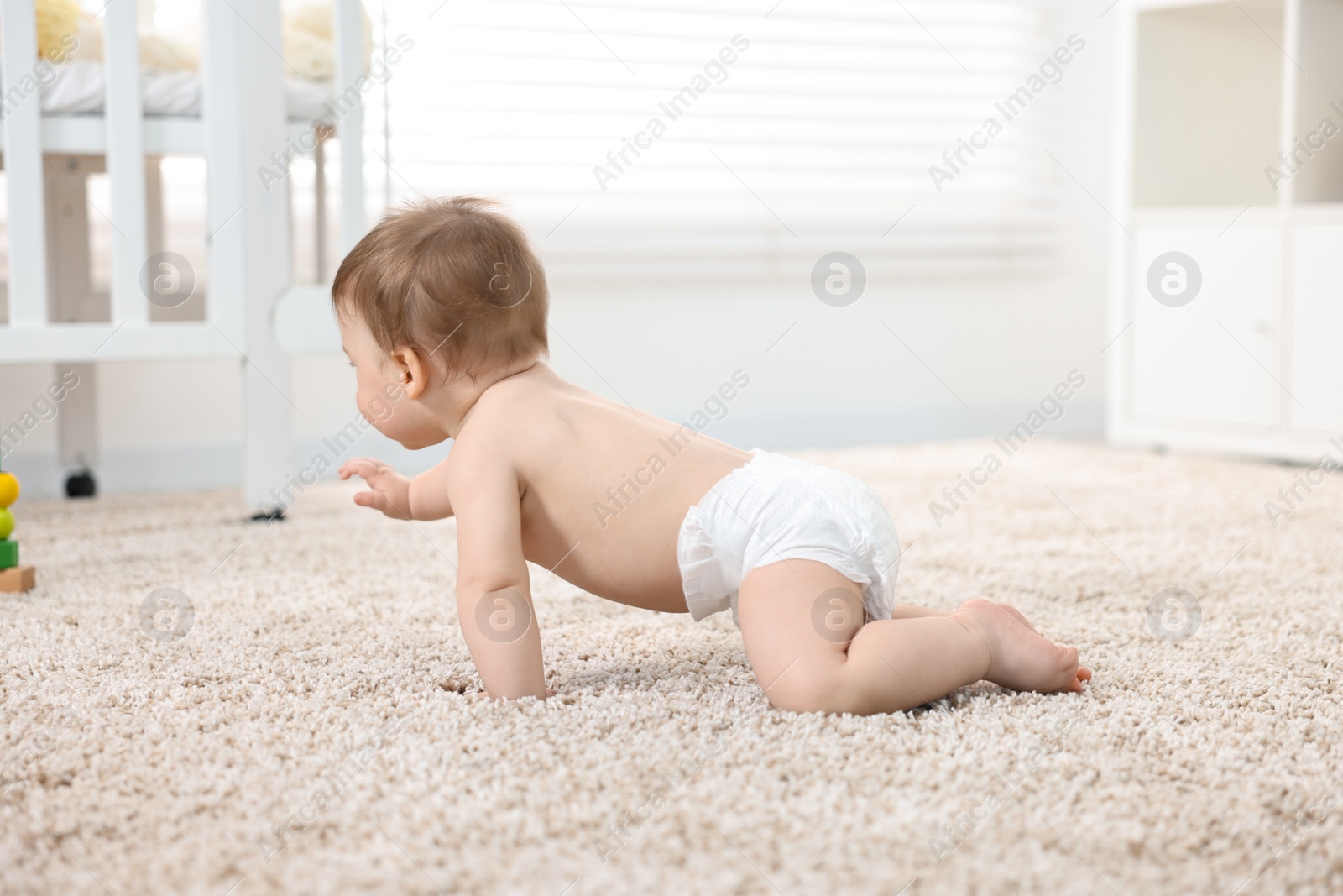 Photo of Baby boy crawling on carpet at home