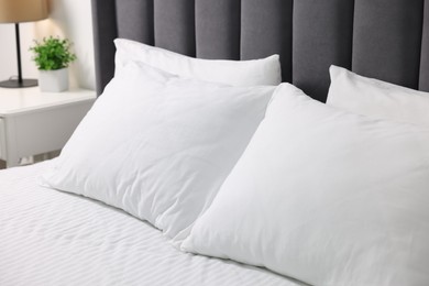 Photo of Soft white pillows and bedsheet on bed at home