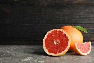 Photo of Fresh tasty grapefruits on table against dark background. Space for text