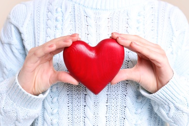Photo of Young woman holding decorative heart in hands, closeup