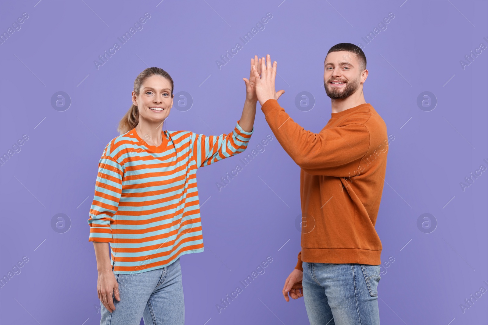 Photo of Happy couple giving high five on purple background