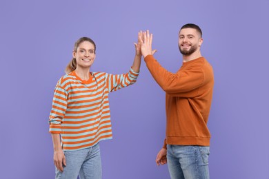 Photo of Happy couple giving high five on purple background