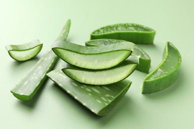 Photo of Fresh aloe vera pieces on green background