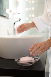 Photo of Young woman taking soap bar to wash hands in bathroom, closeup
