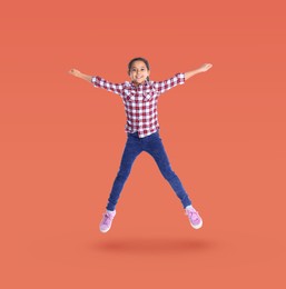 Happy cute girl jumping on coral background